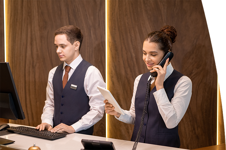 two young hotel receptionists standing by counter